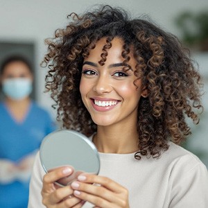 Woman smiling while holding small mirror