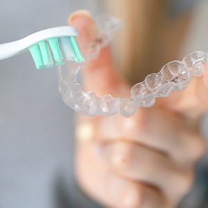 Patient using toothbrush to clean clear aligners