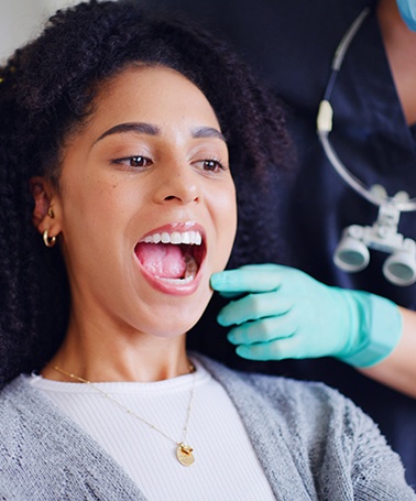 Patient in Roswell looking at teeth in mirror after full mouth reconstruction 