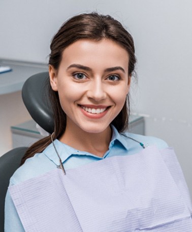 Female patient sitting in dental chair and smiling