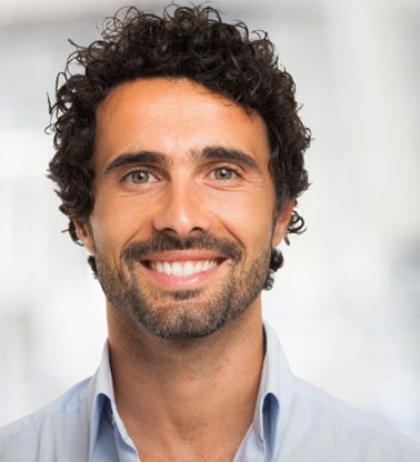 Bearded man in button-up shirt standing and smiling