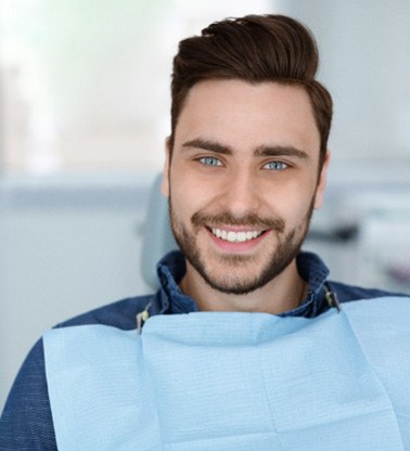 Male dental patient sitting in chair and smiling