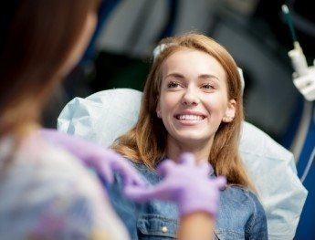 patient smiling at team member while laying in dental chair in Alpharetta